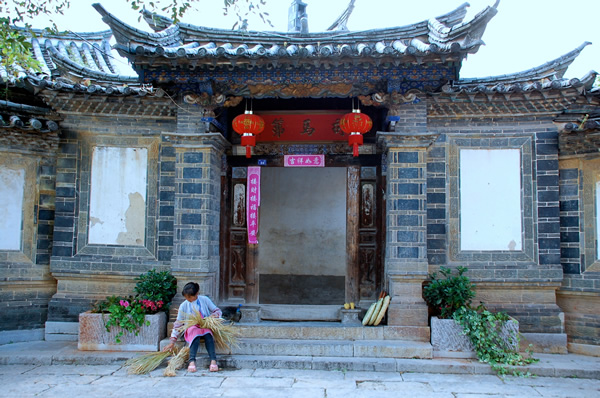 一位手持竹竿的妇女坐在中国寺庙前