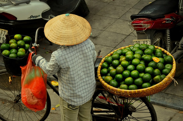 女人从越南河内的自行车出售橙子