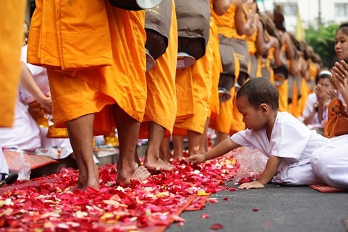 在曼谷的一个佛教节日上，一个男孩伸手去摘玫瑰花瓣