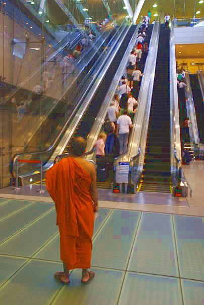 Monk going up escalator in Singapore