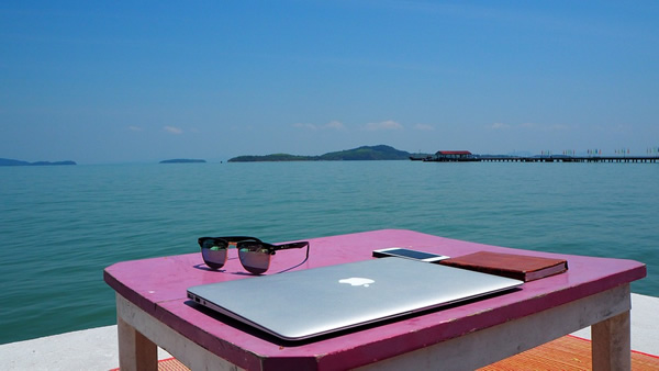 泰国数字游牧民自由职业者与笔记本电脑俯瞰海洋